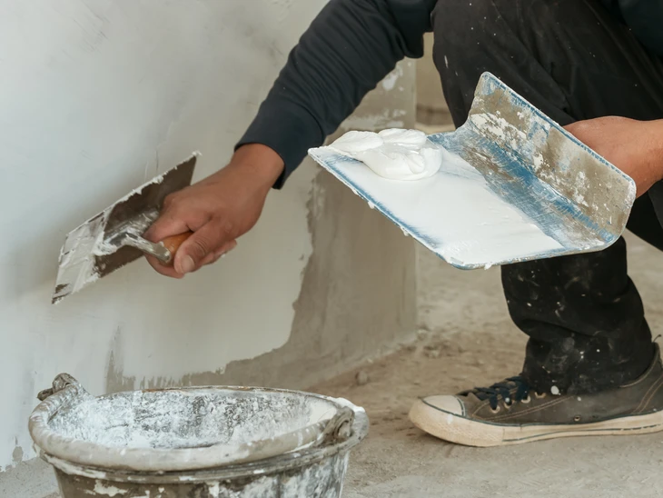 Trois professionnels du bâtiment en réunion de chantier dans un espace en rénovation