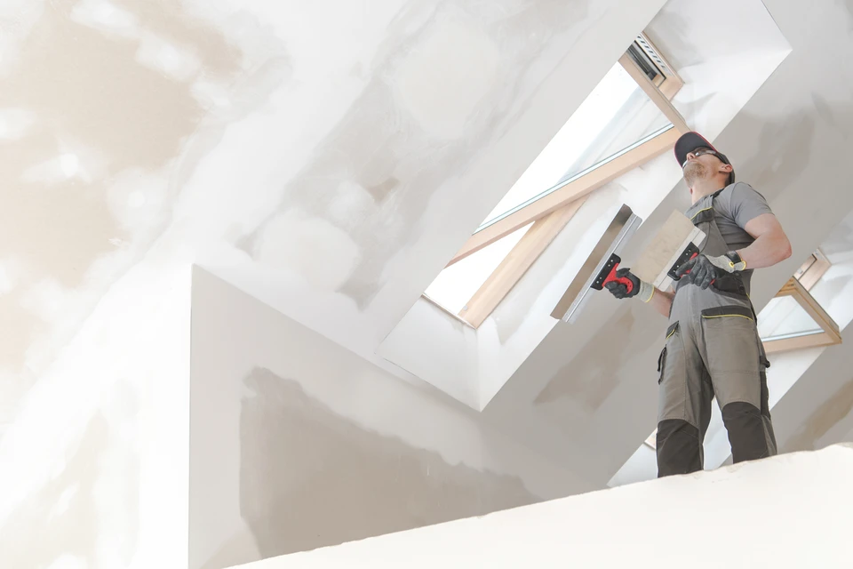 Cuisine moderne blanche avec îlot central, sol carrelage brillant, poubelle inox à pédale au premier plan