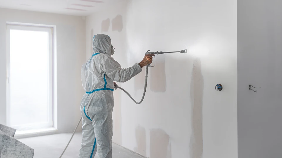 Femme peignant un mur intérieur en bleu turquoise avec rouleau à peinture dans appartement en cours d'aménagement