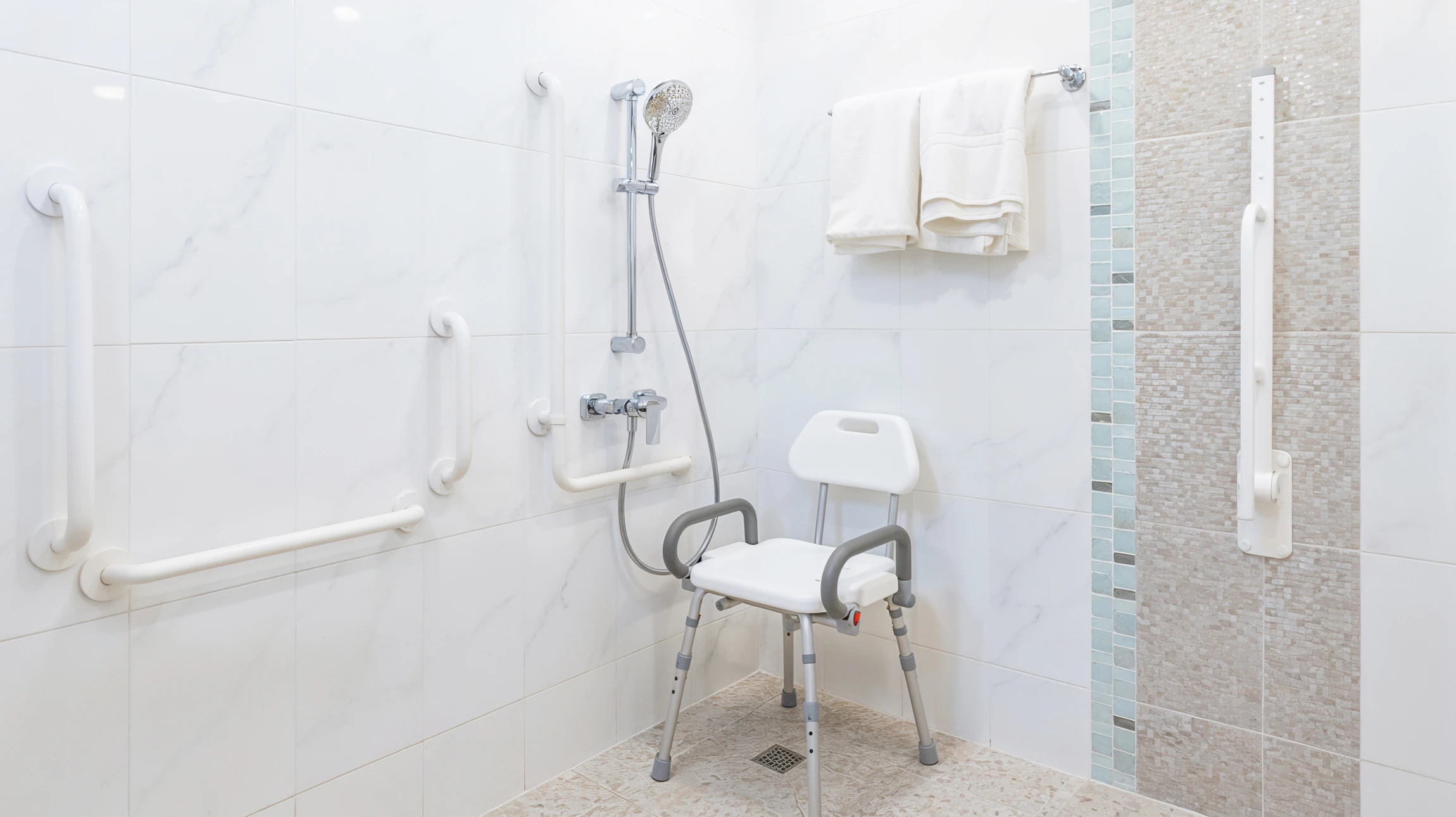 Intérieur de salle de bain carrelée blanc, main âgée saisissant une barre d'appui murale pour assistance à la mobilité