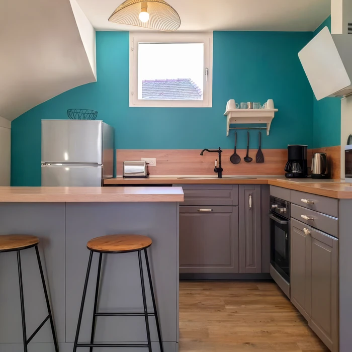 Cuisine moderne compacte avec îlot central et tabourets noirs